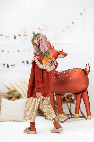 Red deer balloon with white dots and antlers, standing next to a child