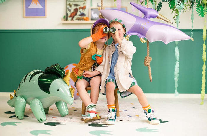 Standing triceratops foil balloon in light green and dark green with gold horns