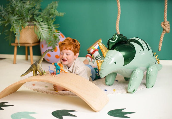 Standing triceratops foil balloon on the floor in light green and dark green