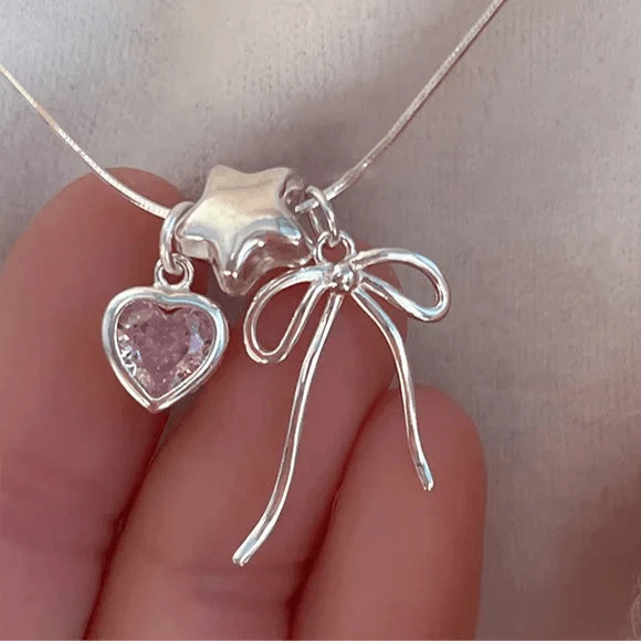 Star and heart necklace charm with pink heart stones and dangling bow on silver chain