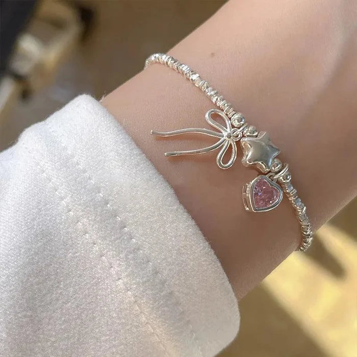 Star and heart bow bracelet with pink heart stones and silver chain on wrist
