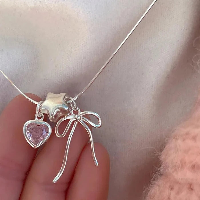 Silver-tone necklace with two heart charms, star charm, and bow detail