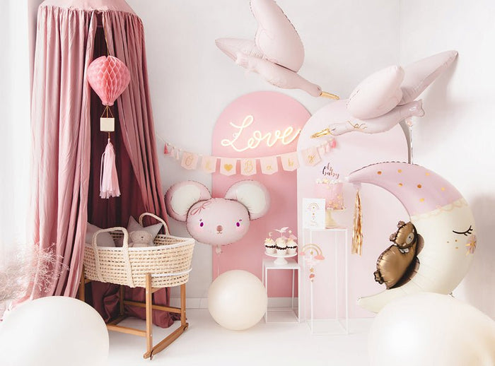 Stork balloon in pale pink and white with gold beak, hovering above pink party decor.