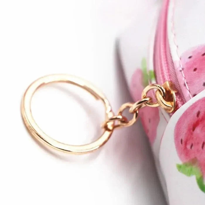 Cosmetics bag zipper pull with gold ring and pink strawberry fabric close-up