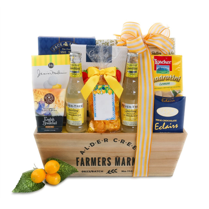 Summer gift basket in wooden crate with ribbon, lemon bottles, and chocolate