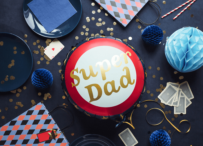Super Dad foil balloon in a party display with navy decorations, blue paper accents, and tassels