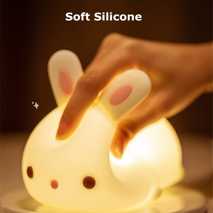 Glowing white bunny night light with soft silicone body and pink ear inserts.