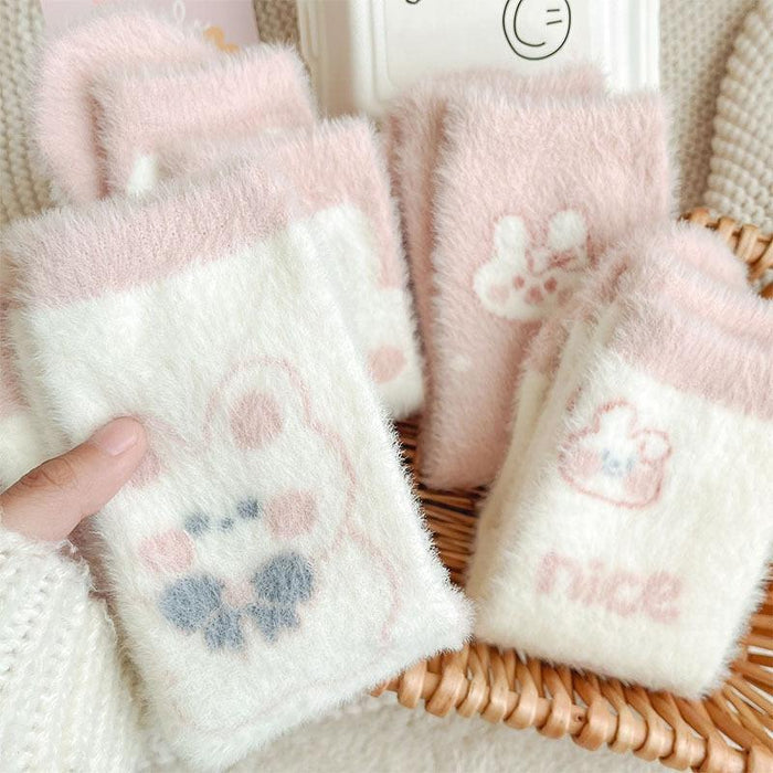 Two folded bunny socks in light pink and white with embroidered paw and bow motifs