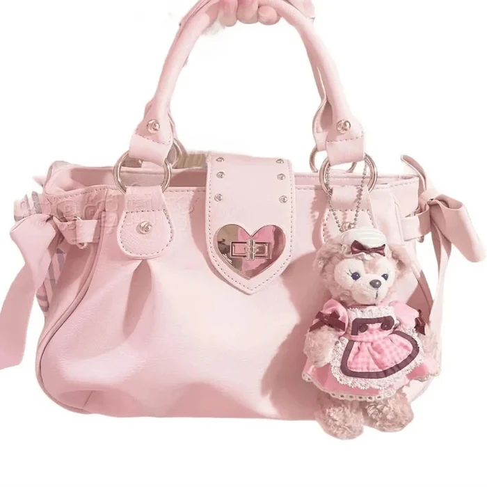 Pink heart-lock handbag with teddy keychain charm, ribbon bows, and studded heart front patch