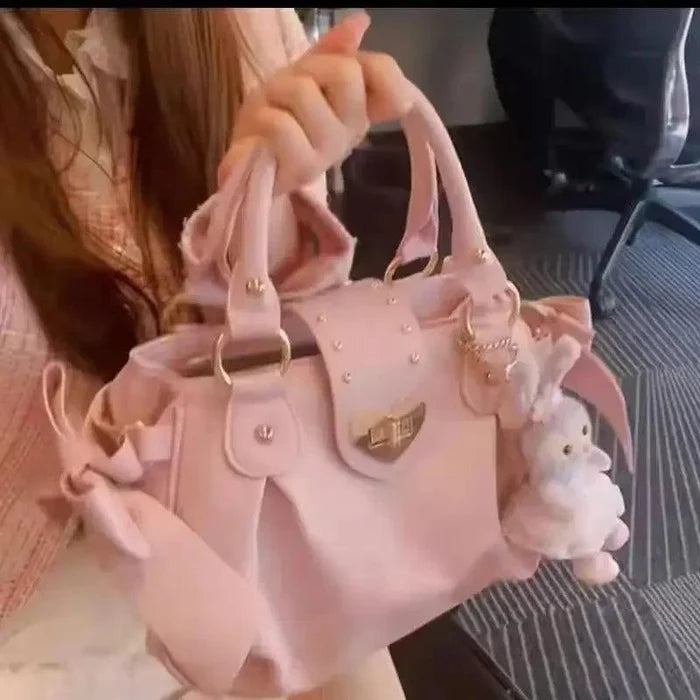 Pink heart-lock handbag in hand with heart crest emblem and plush rabbit charm