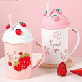 Strawberry-themed lidded mugs with straws, white and pink, on round bases