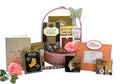 Pink wicker gift basket with 'Mom' box, cookies, crackers and chocolate treats