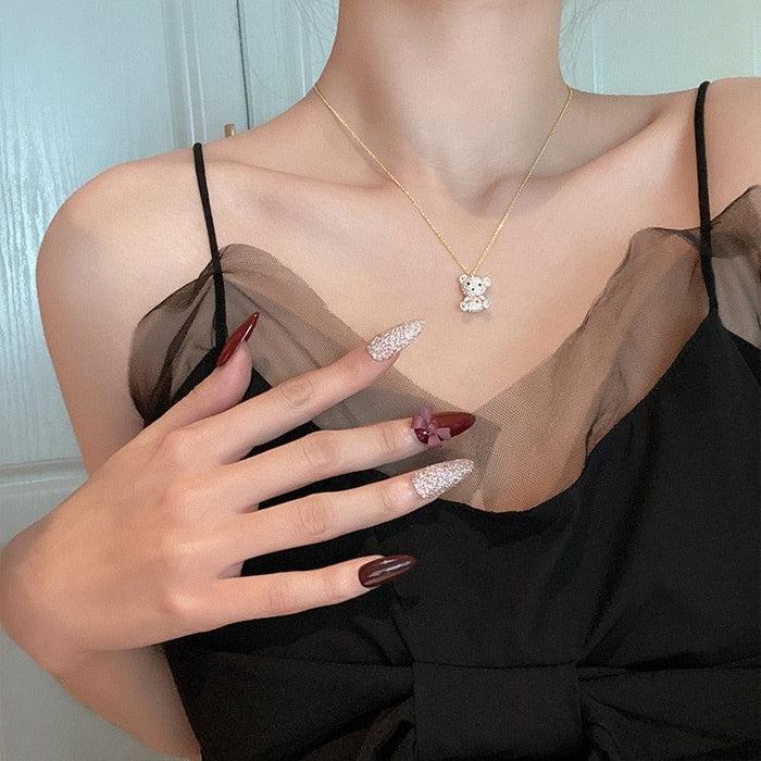 Gold-tone teddy bear pendant necklace worn on a black dress neckline