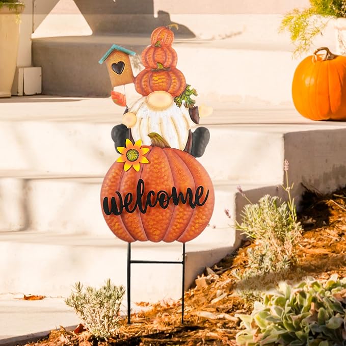Orange pumpkin welcome gnome yard sign on metal stakes with teal house and sunflower.