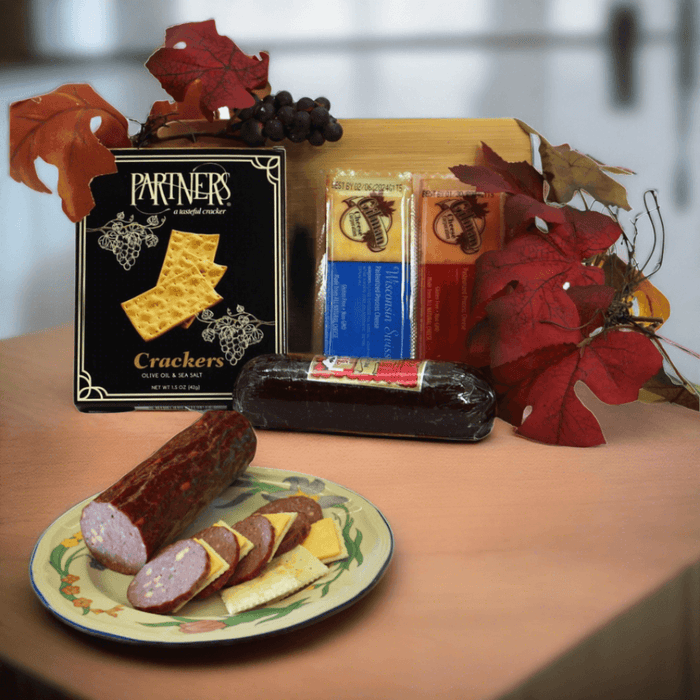 Charcuterie board gift set: crackers, sausage, grapes, and autumn leaves