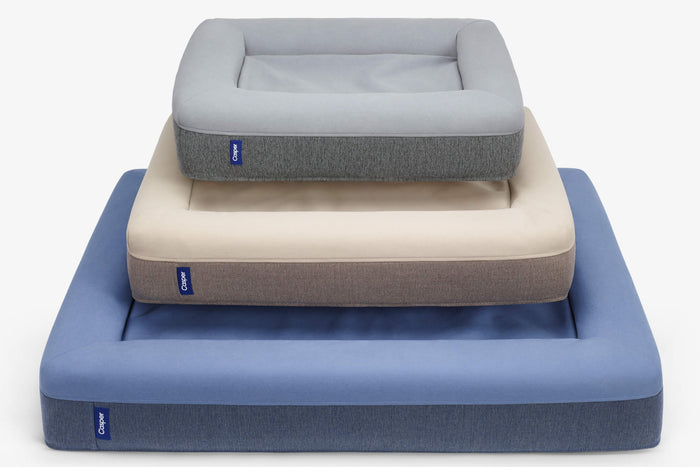 Three sizes of the Dog Bed stacked on top of each other - gray, sand, and blue.