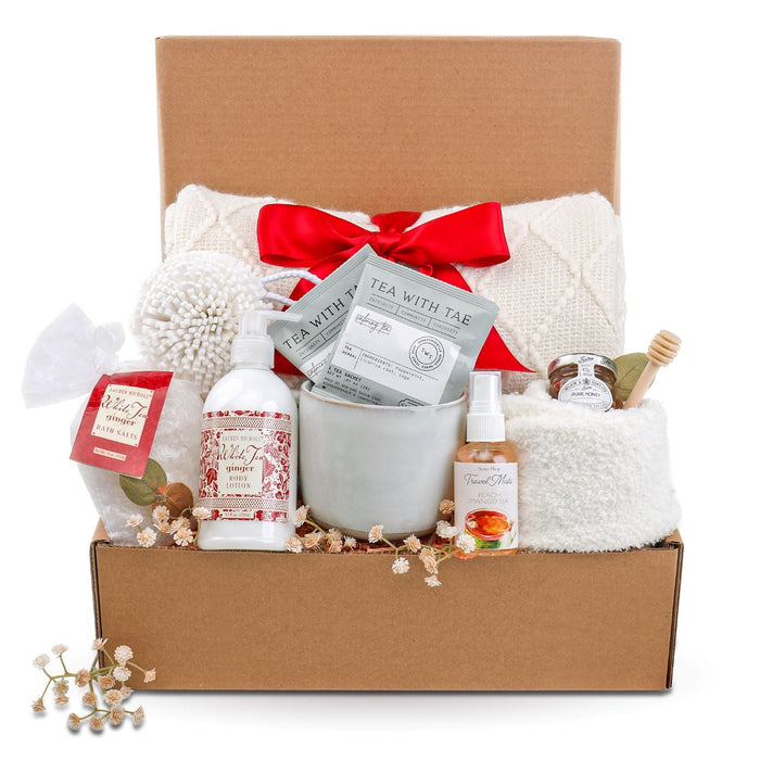 Open gift box with red ribbon, assorted bath and tea items