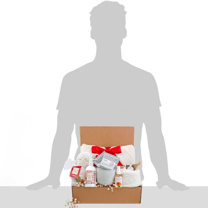 Gift box held by person silhouette, red bow and bath set items