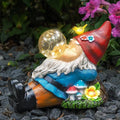 Lying garden gnome statue with red cap, blue shirt, and glowing solar bubble light