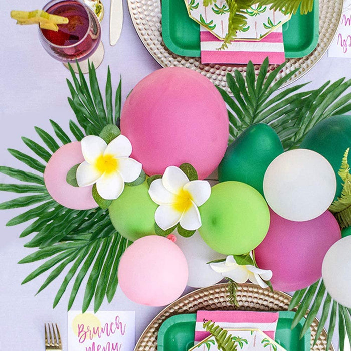Green tropical leaf cutouts with pink and green balloons for party decor
