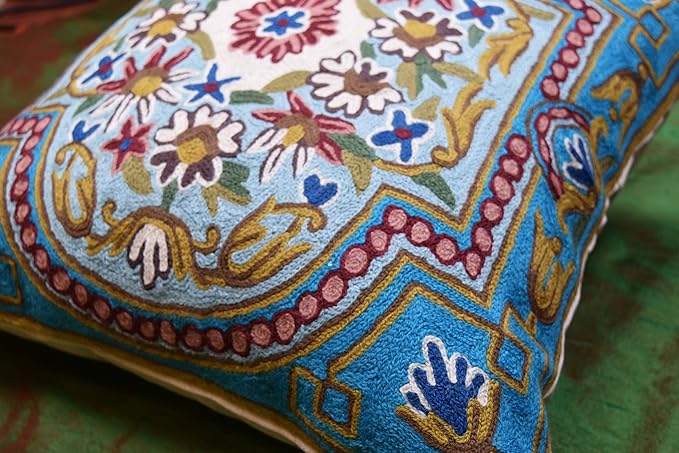 Turquoise pillow cover detail with multicolor floral embroidery and decorative border trim