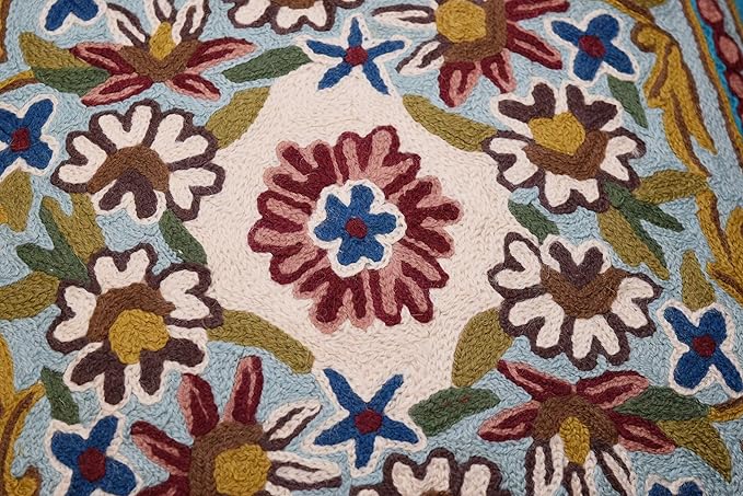 White and multicolor floral embroidery on turquoise pillow cover fabric, close-up