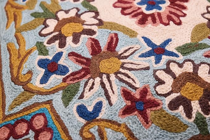 Close-up of multicolor floral embroidery on turquoise pillow cover, textured stitches