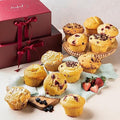 Assorted muffins on a plate with strawberries and blueberries, next to a boxed set