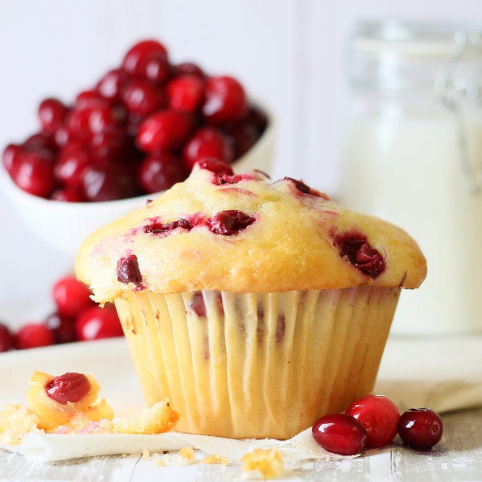 Vanilla muffin topped with red berries, with more berries nearby