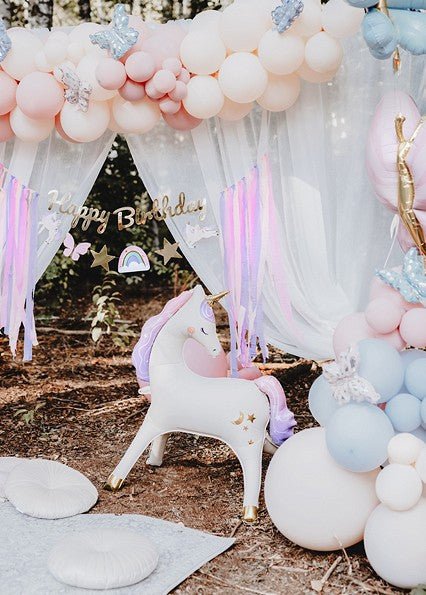Unicorn balloon standing near a balloon arch with pink and white accents