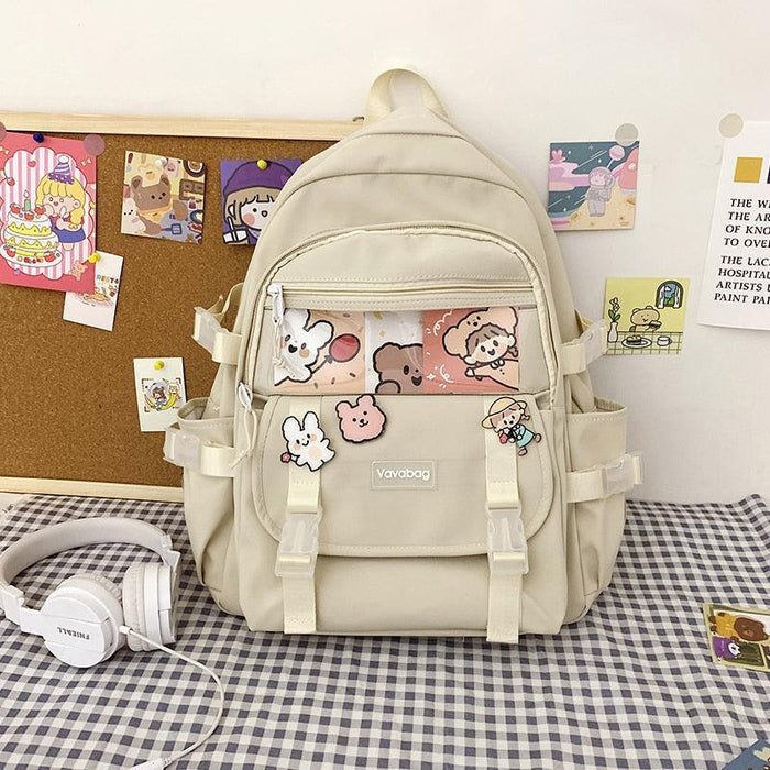 Beige mini backpack with front pockets, cartoon panel, and top handle
