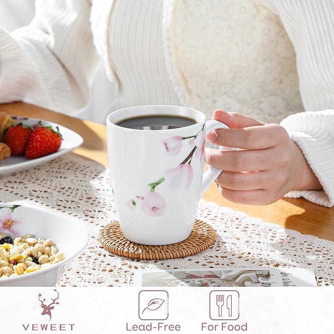 Floral ceramic coffee mug, white with pink blossoms, held by hand