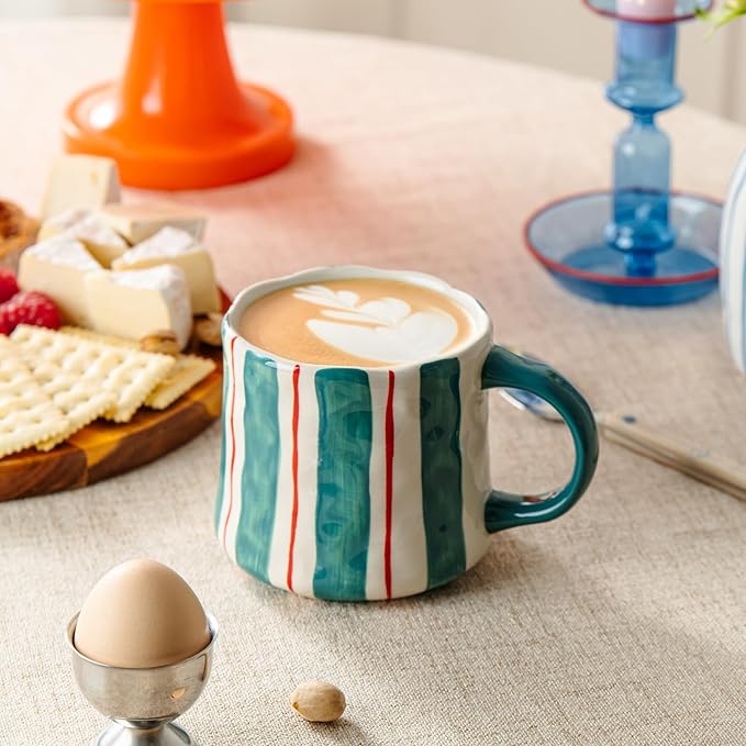 Ceramic coffee mug with teal and red vertical stripes, filled latte, side view