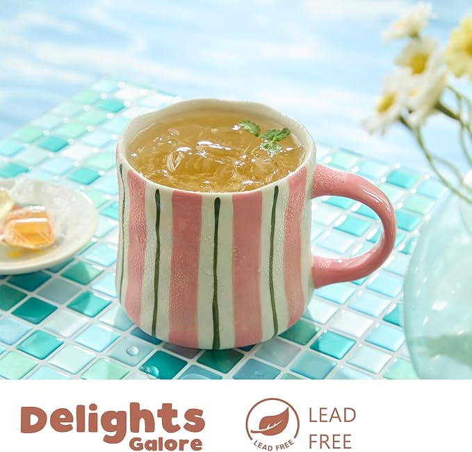 Striped ceramic coffee mug in pink with green vertical lines, filled with hot tea