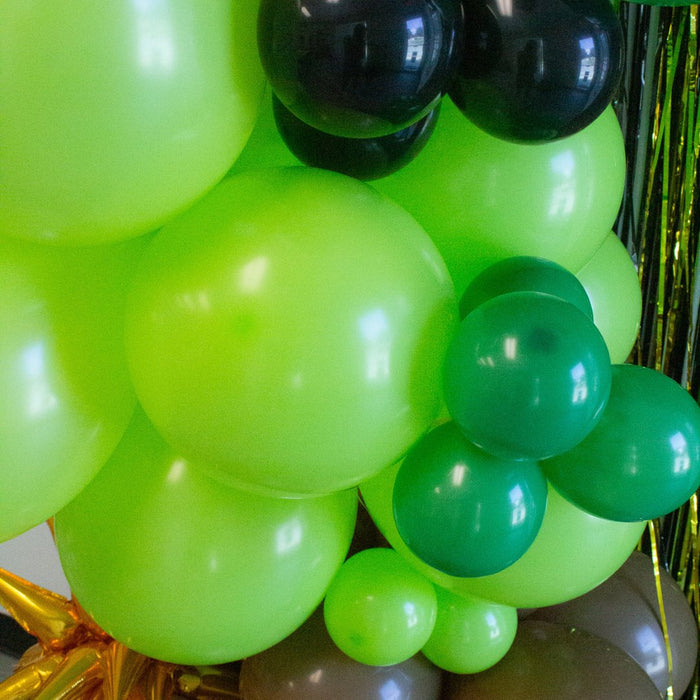 Close-up of lime green balloon cluster with gold tinsel strands at right