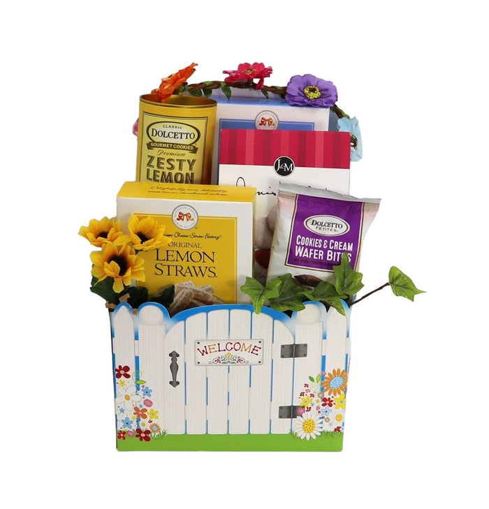 Welcome gift basket with colorful dessert boxes and flower accents, white fence panel