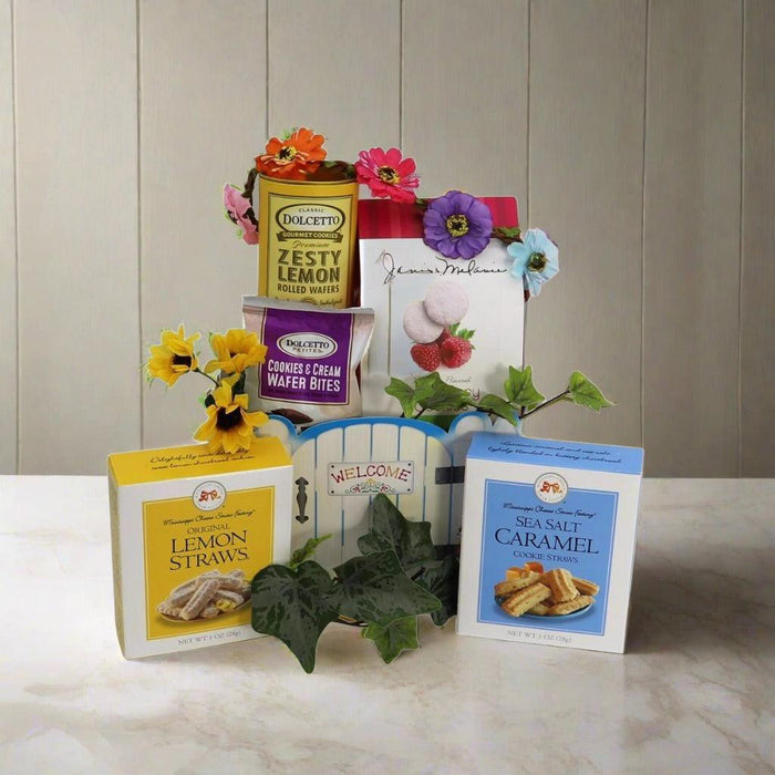 Welcome gift basket with lemon and caramel dessert boxes, cookies, and leafy greenery