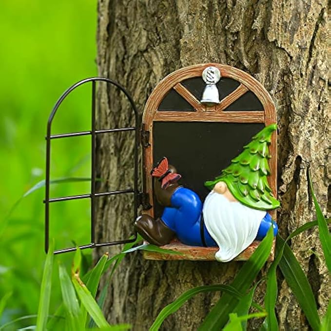 Garden gnome statue in a tree-mounted window frame with green tree and red butterfly