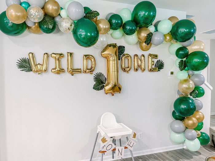 Green and gold balloon garland with gold “Wild One” foil balloon letters