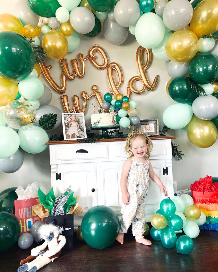 Green, gold, and white balloon garland with gold “Wild One” letters