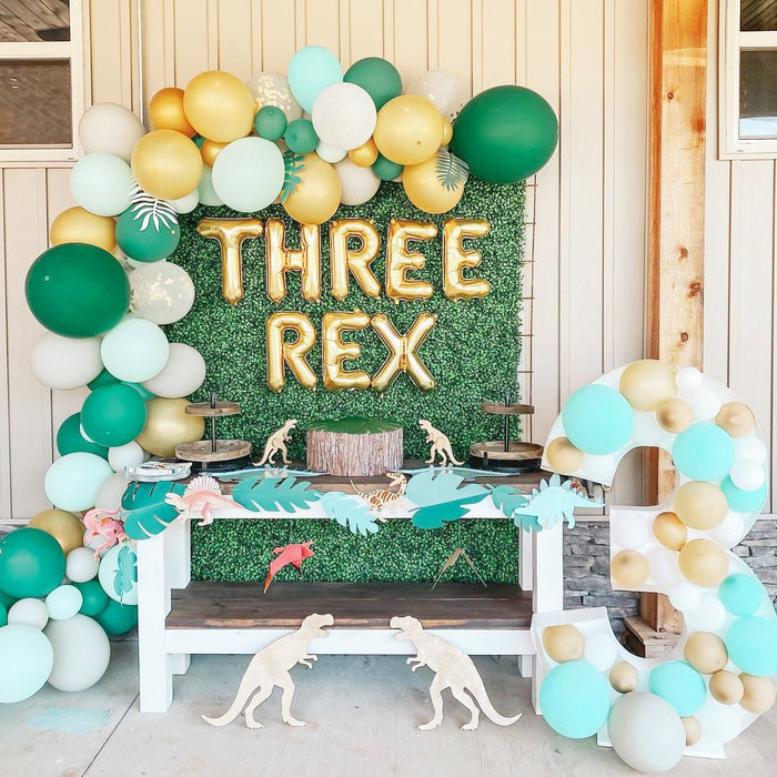 Green and gold balloon garland with large “Three Rex” foam backdrop topper