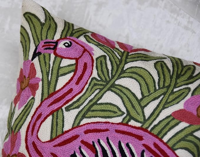 Close-up embroidered flamingo and leaves on cream pillow cover with pink accents