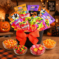 Halloween treat gift basket in black cauldron with orange bow and candy bags plus 3 candy bowls