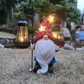 Outdoor gnome statue holding a solar lantern with warm LED glow, red hat and white beard