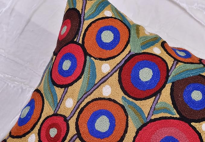 Embroidered wool pillow cover with bold circular designs in blue, red, and orange