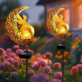 Two gold moon fairy solar stake lights with cracked glass globe and angel cutout