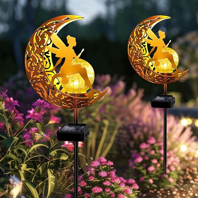 Two gold moon fairy solar stake lights glowing over pink flowers with cracked glass globes