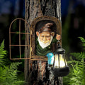 Outdoor resin garden gnome statue holding a solar lantern on a tree trunk