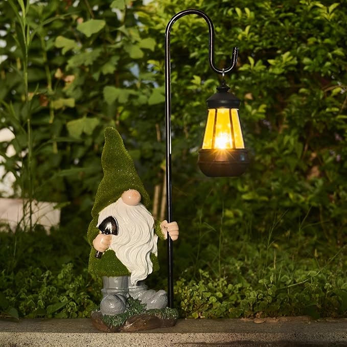 Outdoor solar gnome statue with lit lantern, green hat and white beard, standing in garden